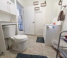 Bathroom featuring baseboards, toilet, vanity, and tile patterned floors