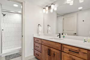 Full bath featuring large  vanity, and tiled shower