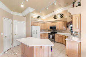 Kitchen with light tile patterned floors, light brown cabinets, stainless steel appliances, light countertops, and track lighting