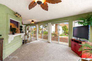 Unfurnished sunroom with a ceiling fan and carpet flooring