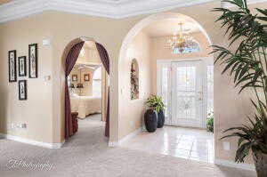 Entrance foyer with baseboards, a notable chandelier, arched walkways, and carpet floors