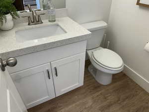 Bathroom featuring wood finished floors, vanity, toilet, and baseboards