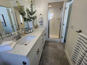 Bathroom featuring stone finish floor, a sink, and a stall shower