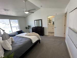 Carpeted bedroom with vaulted ceiling, visible vents, baseboards, a textured ceiling, and ensuite bathroom