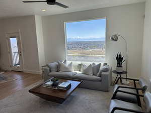 Living area with baseboards, a ceiling fan, wood finished floors, and a textured ceiling