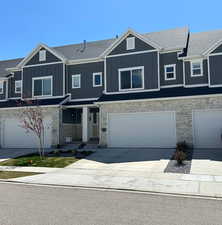Different but similar property with stone siding, driveway, board and batten siding, and a garage