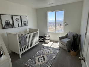 Carpeted bedroom with a nursery area, a textured ceiling, and visible vents