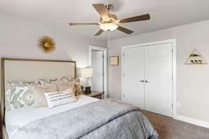 Carpeted bedroom with ceiling fan, baseboards, and a closet