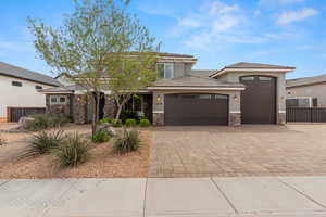 Prairie-style house featuring an attached garage, driveway, stone siding, and stucco siding