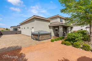 View of front of home featuring a jacuzzi, a gate, a fenced backyard, stucco siding, and a patio