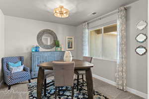 Carpeted dining space featuring baseboards, visible vents, and an inviting chandelier