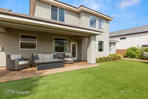 Back of house with an outdoor living space, a lawn, a patio, and stucco siding
