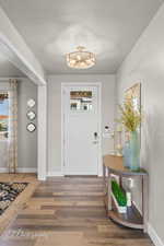 Entrance foyer with baseboards, wood finished floors, and a textured ceiling