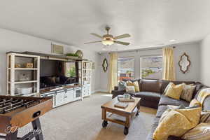 Living room featuring light carpet, visible vents, a textured ceiling, and ceiling fan