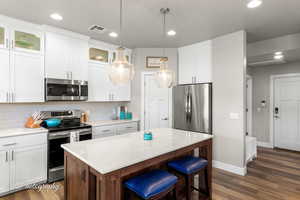 Kitchen featuring stainless steel appliances, a center island, tasteful backsplash, visible vents, and dark wood-type flooring