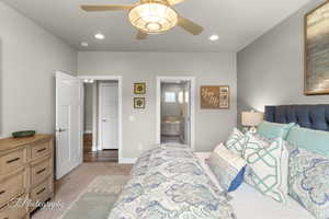 Carpeted bedroom featuring baseboards, ensuite bath, recessed lighting, and ceiling fan