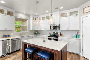 Kitchen with stainless steel appliances, a center island, a sink, visible vents, and light countertops