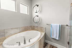 Full bath featuring a bath, wood finished floors, and baseboards