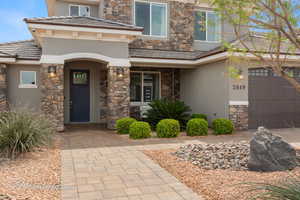 View of front facade featuring stucco siding, a tile roof, and stone siding