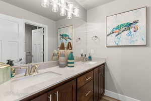 Full bath featuring double vanity, baseboards, and a sink