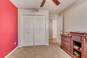 Bedroom featuring baseboards, light carpet, visible vents, and a closet