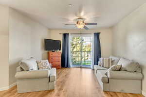 Living room with ceiling fan, baseboards, and light wood-style flooring