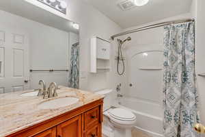 Bathroom featuring tile patterned flooring, visible vents, toilet, vanity, and shower / tub combo with curtain