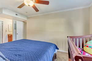 Bedroom with ceiling fan, carpet, baseboards, ornamental molding, and visible vents