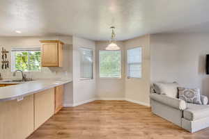 Kitchen featuring open floor plan, light wood-style floors, light brown cabinets, and a sink