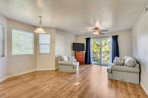 Sitting room featuring a ceiling fan, a textured ceiling, light wood-style floors, baseboards, and visible vents