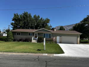 Ranch-style home featuring brick, new paint siding, a chimney, an attached garage, a front lawn, and driveway