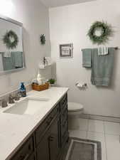 Bathroom with toilet, vanity, and tile patterned floors