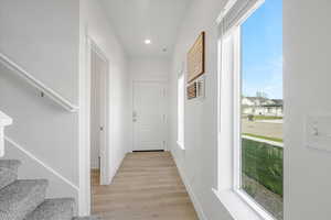 Hallway with light wood-style flooring, baseboards, recessed lighting, and stairs