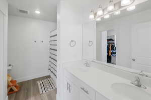 Bathroom featuring double vanity, wood finished floors, visible vents, and a sink