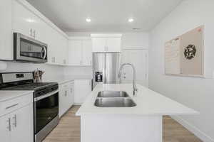 Kitchen with a sink, visible vents, light countertops, an island with sink, and appliances with stainless steel finishes