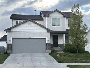 View of front of home featuring brick siding, an attached garage, driveway, and a front lawn