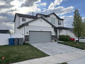 View of front of property featuring a garage, driveway, a front lawn, and fence