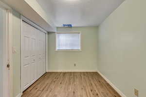 Unfurnished bedroom featuring light wood-type flooring, a closet, and baseboards