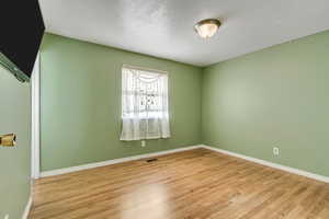 Empty room with baseboards, wood finished floors, and visible vents