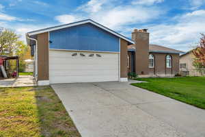 Ranch-style house with a chimney, a front lawn, concrete driveway, fence, and brick siding