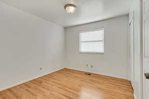 Unfurnished bedroom with light wood finished floors, baseboards, visible vents, and a closet