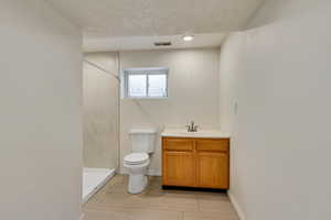 Full bathroom with a tile shower, toilet, baseboards, visible vents, and recessed lighting