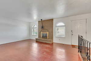 Unfurnished living room featuring baseboards, wood finished floors, and a fireplace