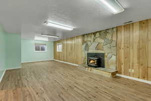 Basement featuring a textured ceiling, baseboards, visible vents, wood finished floors, and wooden walls