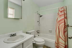 Full bath with toilet, vanity, and shower / bath combination with curtain