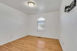 Spare room featuring baseboards, light wood-style flooring, and visible vents