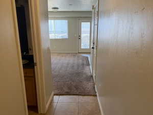 Hall with light tile patterned flooring and baseboards