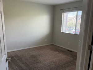 Carpeted spare room with a textured ceiling, visible vents, and baseboards