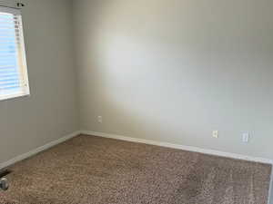 Carpeted spare room featuring baseboards