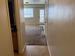 Hall featuring a textured ceiling, visible vents, tile patterned floors, and baseboards